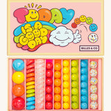 Billes & Co marbles in today's a good day inspired set. Features 67 rainbow coloured  glass marbles with a mixture of textured and flat marbles. Comes in a pale pink coloured box with a playful design of a cloud and rainbow. 