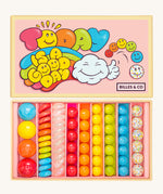 Billes & Co marbles in today's a good day inspired set. Features 67 rainbow coloured  glass marbles with a mixture of textured and flat marbles. Comes in a pale pink coloured box with a playful design of a cloud and rainbow. 