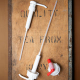 A Bio-D 5L screw on pump lying next to a 20L pump and tap adapter both available at Babipur. These pumpscan be used on any 5L and 20L Bio-D liquid for easy refilling 