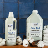 A 5L bottle of Bio-D cotton fresh non bio laundry liquid standing next to a 1L bottle and sprigs of cotton. Both sizes are available at Babipur.