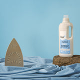 A 1L bottle of Bio-D fragrance free fabric conditioner standing on top of a rock with next to iron. This fabric conditioner is available at Babipur. 