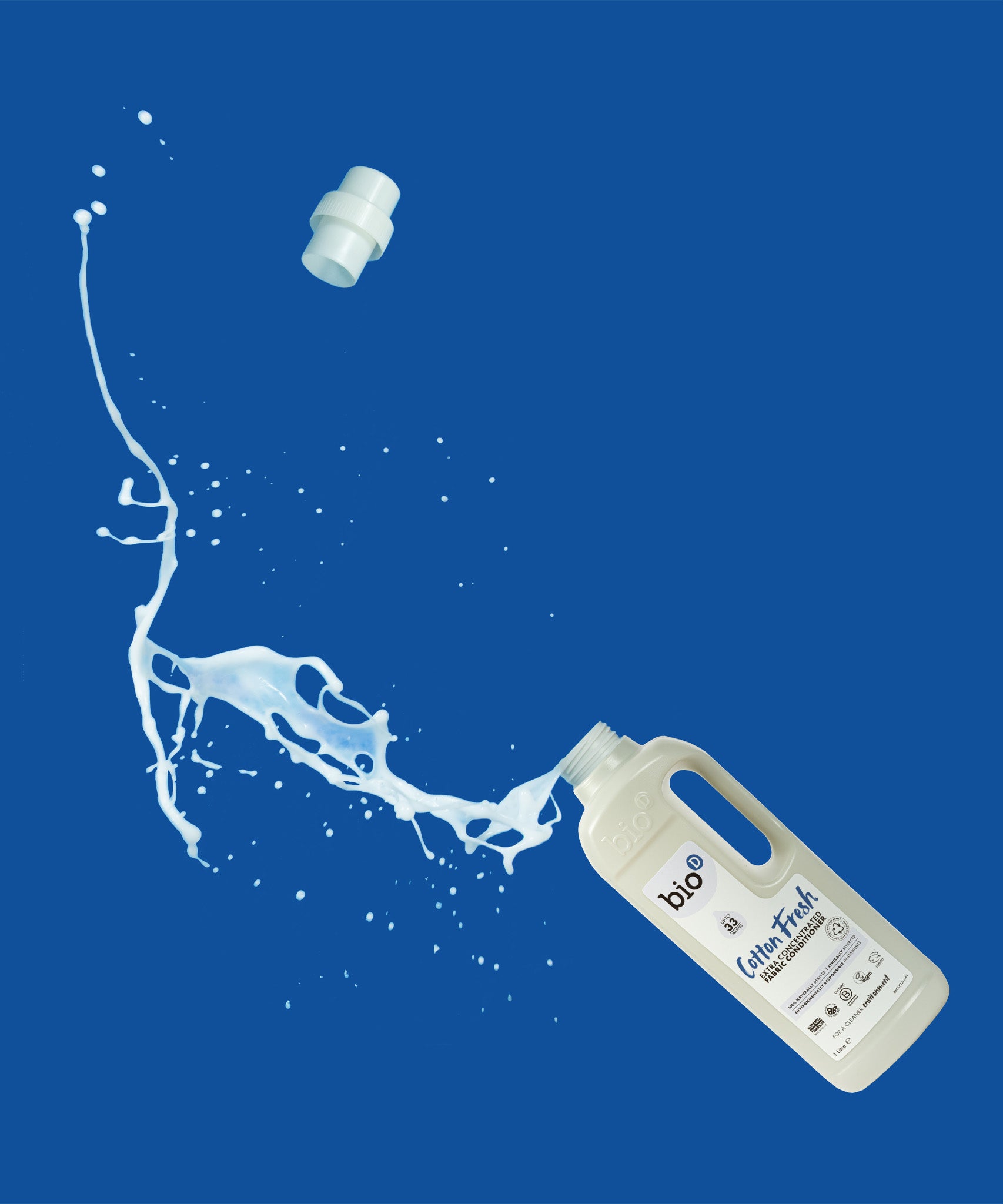 A 1L bottle of Bio-D cotton fresh fabric conditioner laying flat with the liquid spilling out the bottle. This fabric conditioner is available at Babipur.