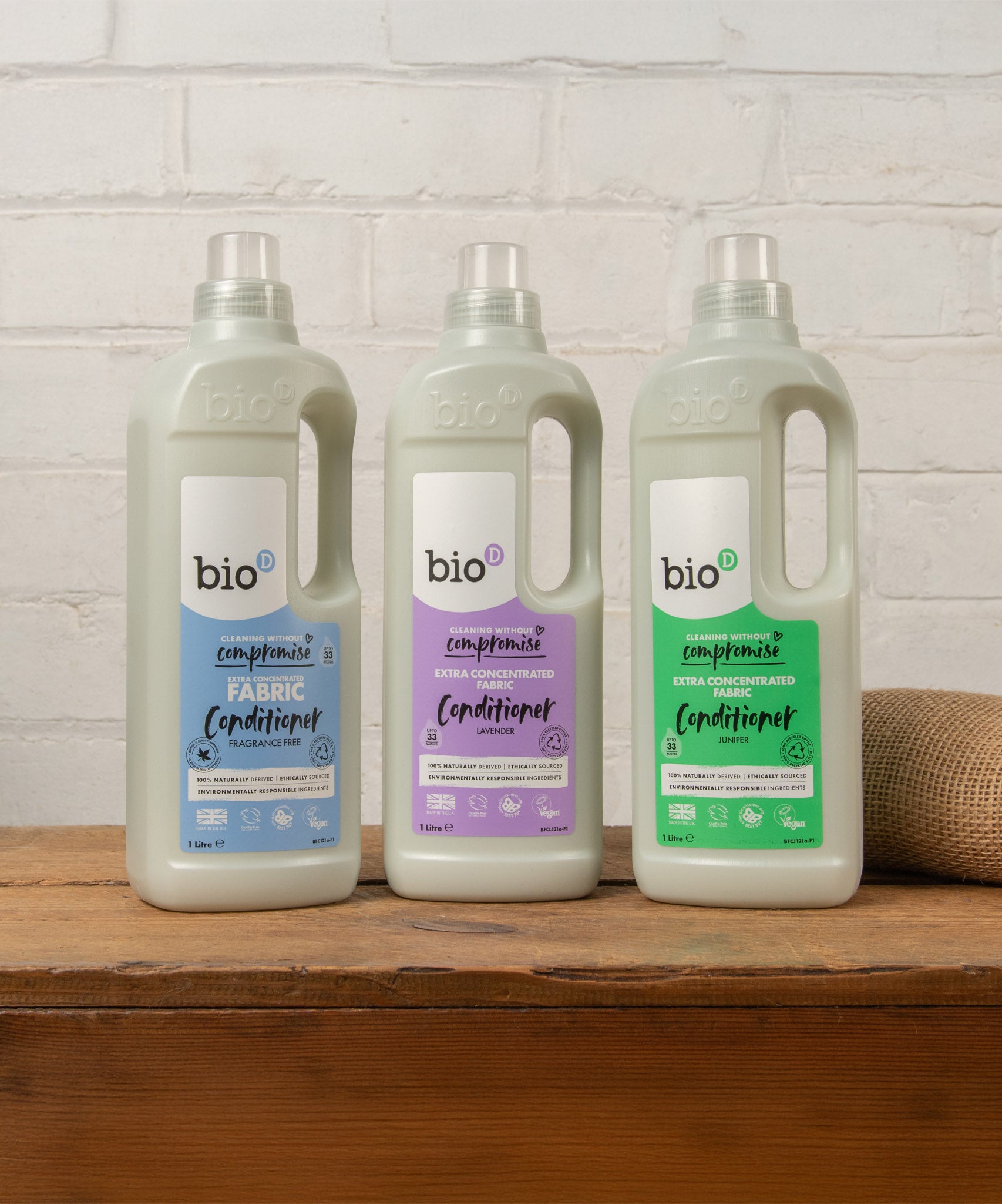 A group of Bio-D fabric conditioner standing on a wooden surface, image showing the fragrance free, lavender and juniper bottles. These are available at Babipur.