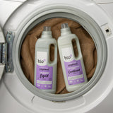 A 1L bottle of Bio-D lavender fabric conditioner and laundry liquid inside a washing machine. Both are available at Babipur. 