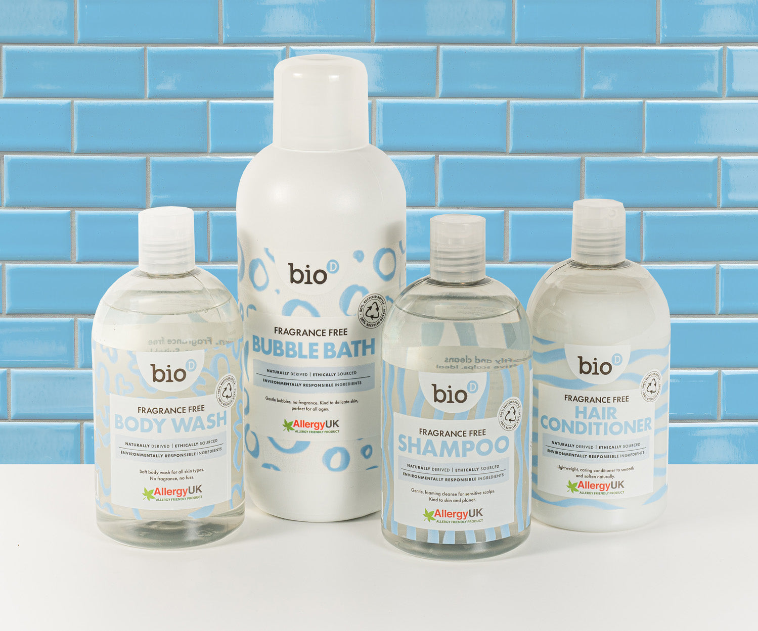Bio-D fragrance-free shampoo, conditioner, body wash and bubble bath bottles shown together against a blue tiled background, presenting Allergy UK approved, refillable body care for sensitive and allergy-prone skin.