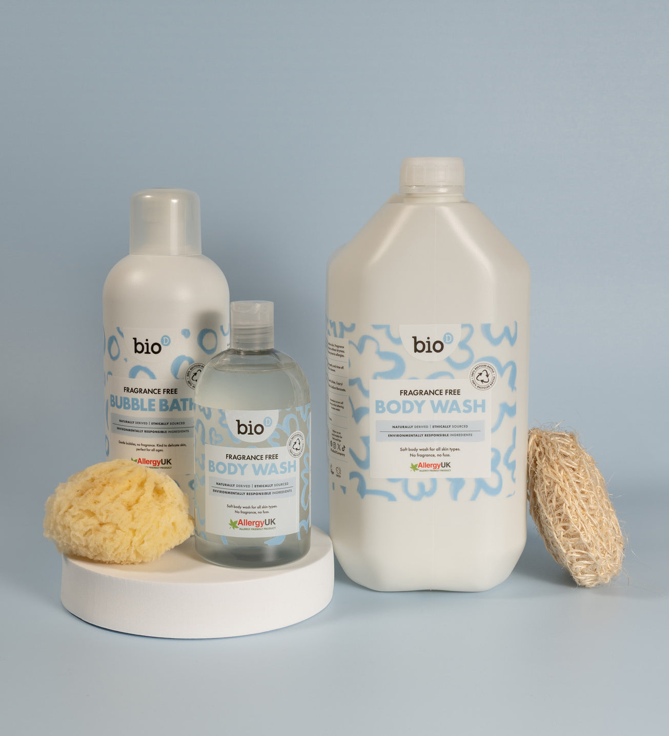 Bio-D fragrance free body wash shown alongside a bubble bath bottle and a 5 litre refill bottle, arranged with a natural sponge and loofah.