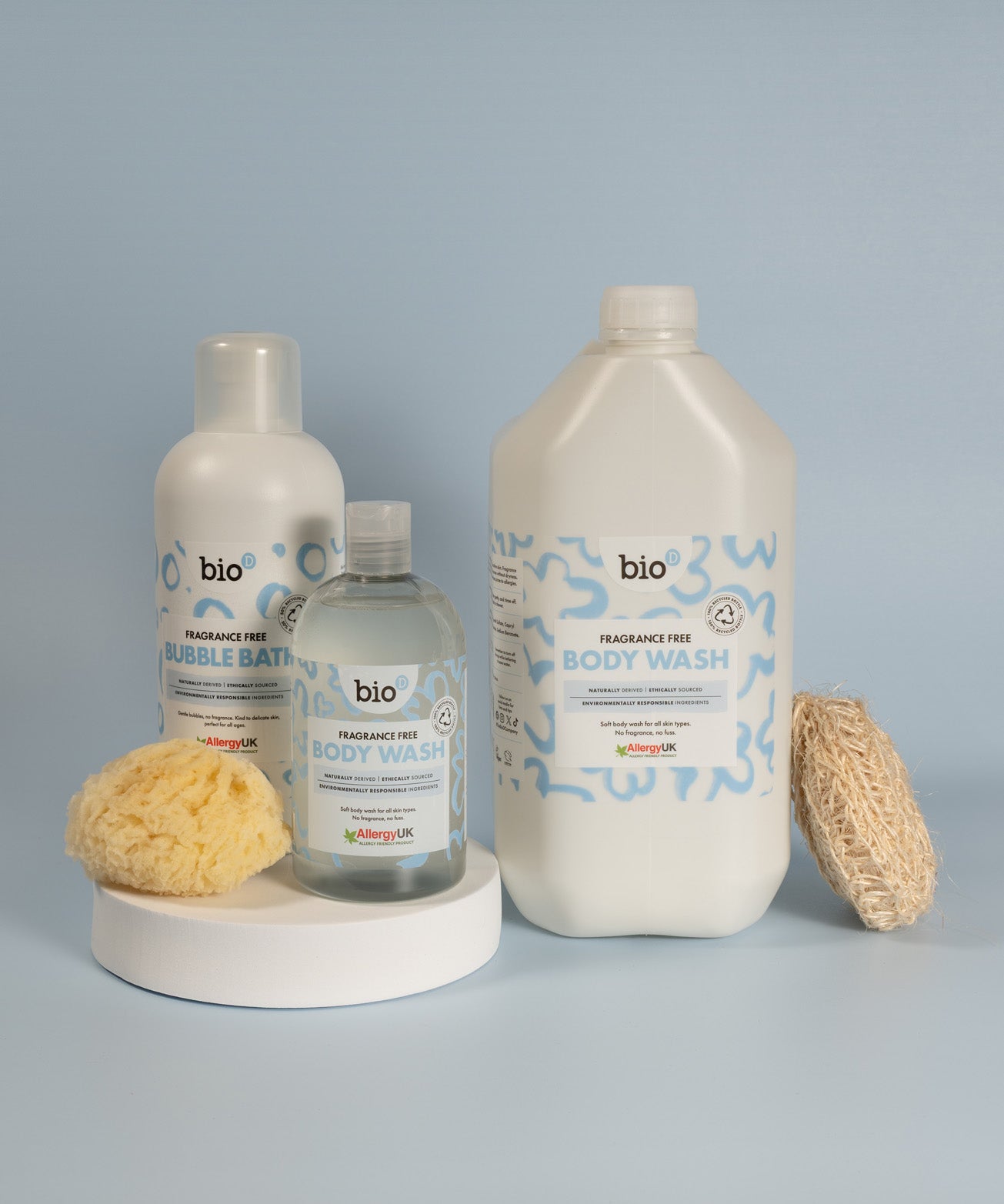 Bio-D fragrance free body wash shown alongside a bubble bath bottle and a 5 litre refill bottle, arranged with a natural sponge and loofah.