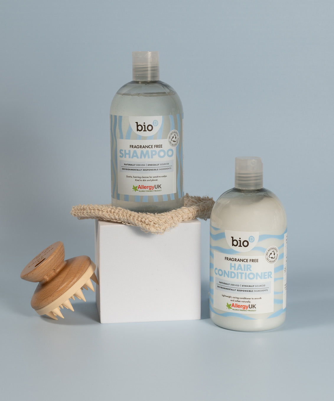 Bio-D fragrance-free shampoo and hair conditioner bottles displayed with a wooden scalp brush, showing gentle, allergy-friendly hair care for sensitive scalps.