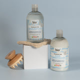 Bio-D fragrance-free shampoo and hair conditioner bottles displayed with a wooden scalp brush, showing gentle, allergy-friendly hair care for sensitive scalps.