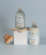 Bio-D fragrance-free shampoo and hair conditioner bottles displayed with a wooden scalp brush, showing gentle, allergy-friendly hair care for sensitive scalps.