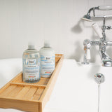 Bio-D fragrance-free shampoo and conditioner on a wooden bath tray beside a bathtub, illustrating refillable, Allergy UK approved hair care suitable for sensitive and allergy-prone skin.