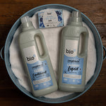 Bio-D fragrance free fabric conditioner 1 litre bottle on a blue back ground surrounded by white clothes