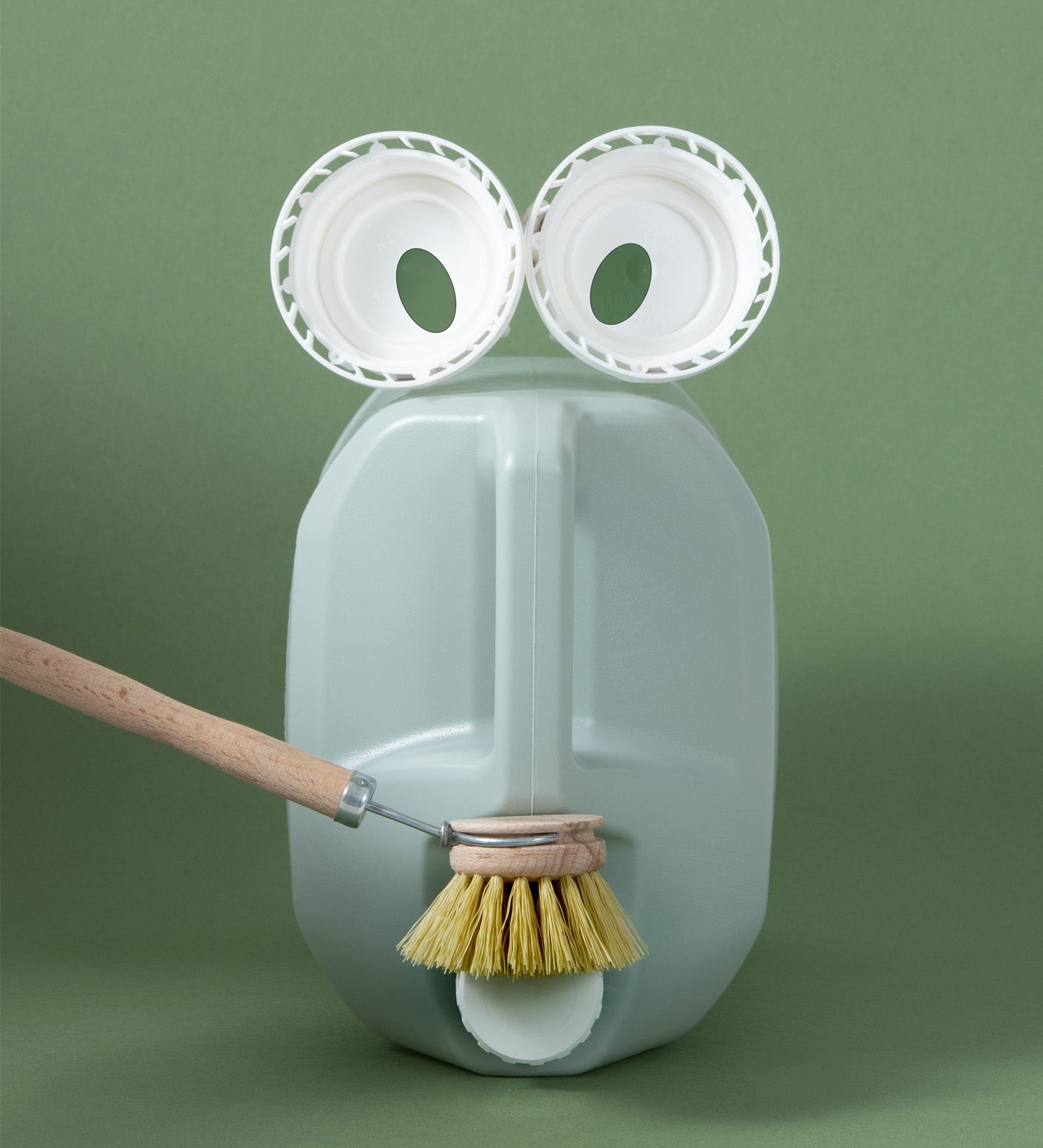 A Bio-D 20 litre closed loop washing up liquid container styled with upcycled lids as eyes and a dish brush for the mouth, emphasising the reusable packaging system supported by Babipur.