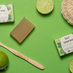 Bio-D natural Vegan aloe vera and lime soap bar on a green background surrounded by limes and a bamboo toothbrush