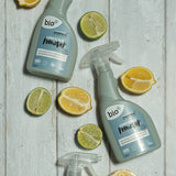 A bottle of Bio-D limescale remover lying flat on a wooden surface next to sliced fruit. This limescale remover is available at Babipur. 