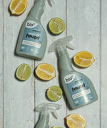 A bottle of Bio-D limescale remover lying flat on a wooden surface next to sliced fruit. This limescale remover is available at Babipur. 