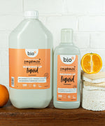 A Bio-D 5Ll mandarin washing up liquid standing next to a  750ml bottle on a wooden surface. Both bottles are available at Babipur 