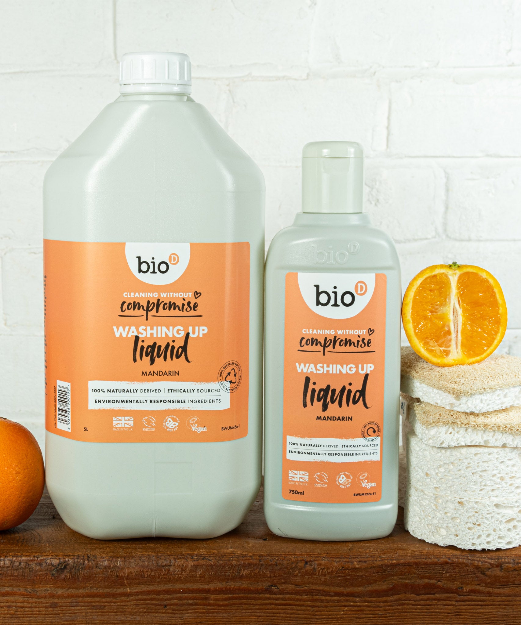 A Bio-D 5Ll mandarin washing up liquid standing next to a  750ml bottle on a wooden surface. Both bottles are available at Babipur 