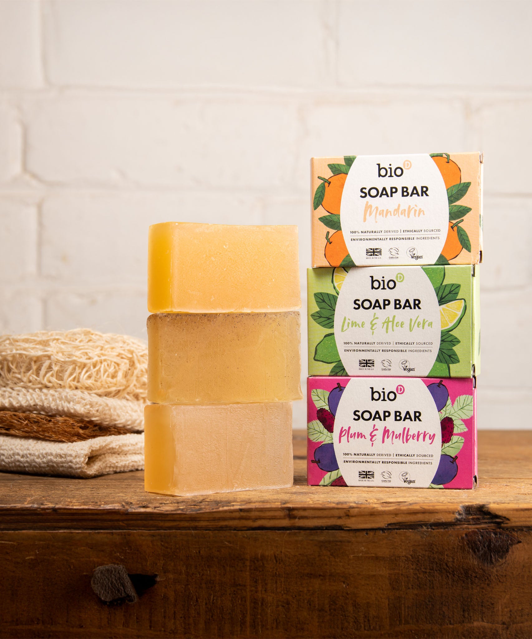 A stack of the 3 different Bio-D soap bars on a wooden surface. These soap bars are available at Babipur