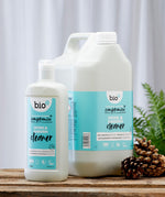 Front view of Bio-D Home and Garden Cleaner bottles in 750ml and 5 litre sizes, standing on a wooden surface with pine cones and greenery to show the refill size alongside the smaller bottle.