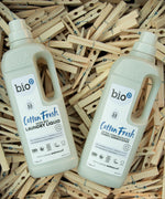 1L Bio-D cotton fresh laundry liquid and fabric conditioner bottles resting on a pile of wooden pegs