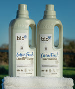 A 1L bottle of Bio-D cotton fresh laundry liquid and fabric conditioner standing on a pile of white towels.