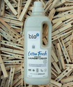 A 1L Bio-D cotton fresh laundry liquid bottle resting on a pile of wooden pegs