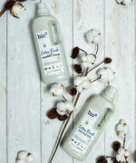 Bio-D cotton fresh laundry liquid and fabric conditioner laid on a wooden surface surrounded by cotton 