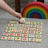 A child picking a tile from the Bajo Wooden Tiles Memory Game. The tile has an illustration of a cherry on it. All the tiles from the set have been laid out and are showing the different illustration. These heirloom quality toys by Bajo are part of a wide range of wooden toys available here at Babipur. 