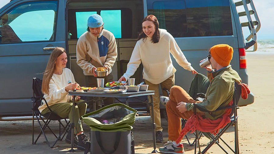 People camping and enjoying their outdoor meals with the Black+Blum stainless steel cutlery, plates, lunchboxes, and cups.