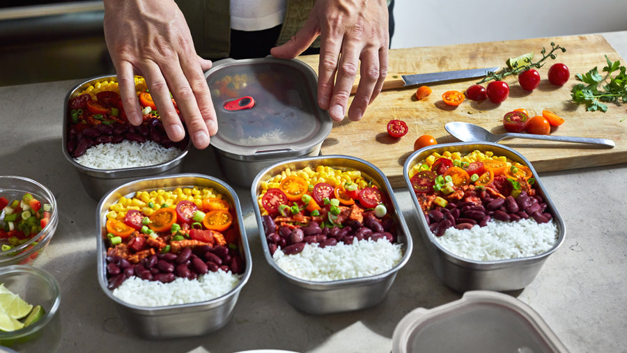 A person using the Black+Blum stainless steel food storage lunch boxes to meal prep.