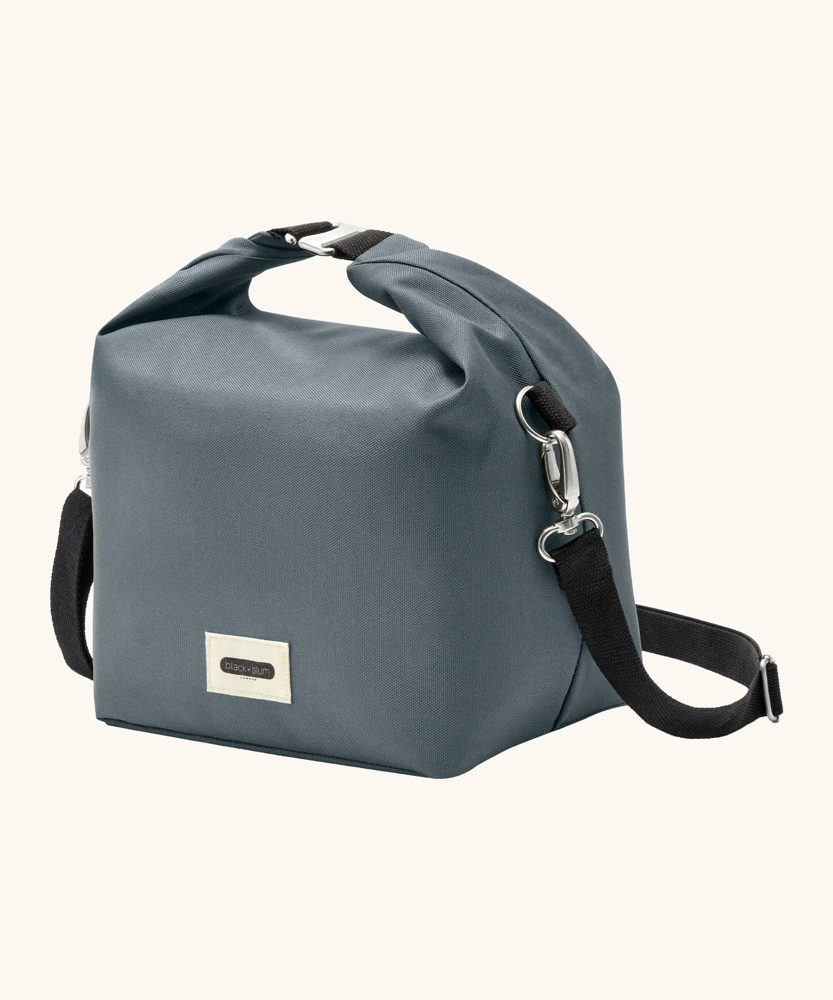 Side of Black+Blum 10 litres insulated and water repellent roll top lunch bag in slate blue showing carry strap hooked on the side loop