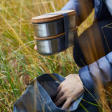 Adult putting in two Black+Blum stainless steel leakproof bento lunchboxes in a backpack