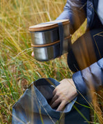 Adult putting in two Black+Blum stainless steel leakproof bento lunchboxes in a backpack