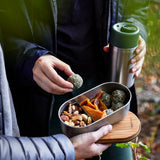 Adult picking up food from a Black+Blum stainless steel leakproof bento box held by another person