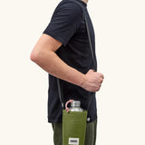 Adult carrying a Black + Blum insulated  bottle bag in moss green over the shoulder showing a flask inside