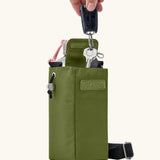 Adult hand storing car keys inside a compartment in the Black + Blum insulated bottle bag in moss green 