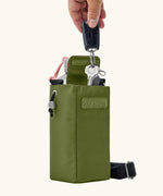 Adult hand storing car keys inside a compartment in the Black + Blum insulated bottle bag in moss green 
