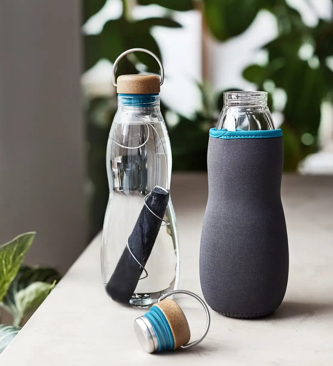 Black + Blum glass bottle with active charcoal water filter and locking coil showing the felted holder and lid detail.