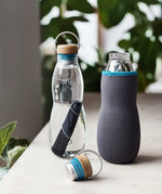 Black + Blum glass bottle with active charcoal water filter and locking coil showing the felted holder and lid detail.