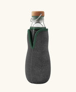 Black + Blum glass bottle with active charcoal water filter and locking coil . Features a felted holder with olive green trim and a cork lid with a loop handle.