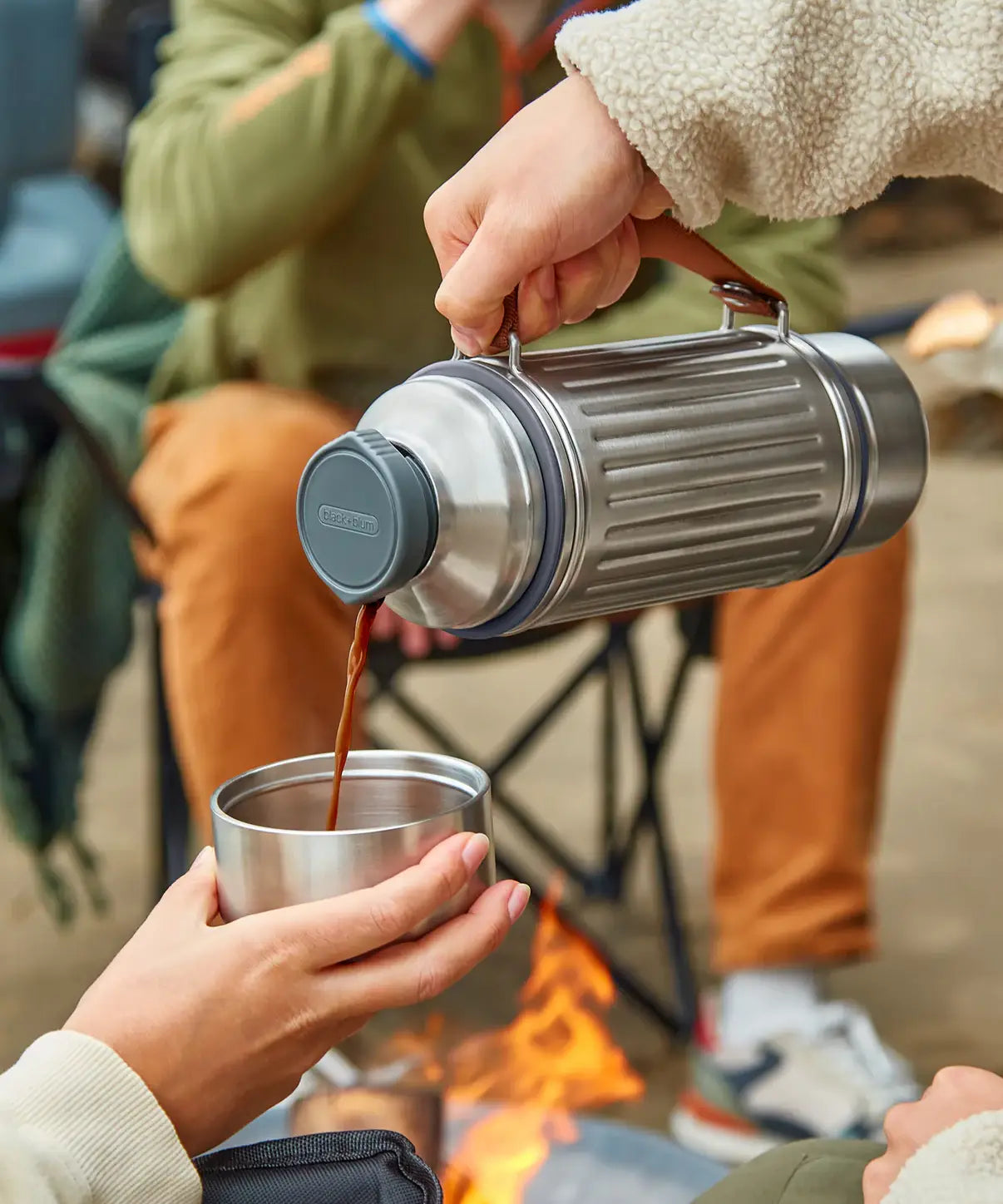 Adult pouring a hot drink into a stainless steel cup using the Black+Blum insulated explorer flask 