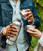 Man unscrewing a double walled cup from the top of the Black+Blum stainless steel explorer flask