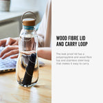 The charcoal filter and spring shown inside the glass bottle from black and blum long side text. The text reads, wood fibre lid and carry loop. the leak proof lid has a polypropylene and wood fibre top and stainless steel loop that makes it easy to carry.  