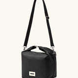 A full Black+Blum 10 litres insulated and roll top lunch bag in black showing the carry strap hooked on the side loops
