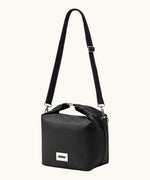 A full Black+Blum 10 litres insulated and roll top lunch bag in black showing the carry strap hooked on the side loops
