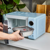 An adult putting a Black + Blum
stainless steel microwave safe leakproof lunchbox inside a microwave for cooking. Lunchbox is available at Babipur.