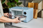 An adult putting a Black + Blum
stainless steel microwave safe leakproof lunchbox inside a microwave for cooking. Lunchbox is available at Babipur.