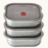 A stack of the Black + Blum square stainless steel leakproof microwave safe lunchboxes 