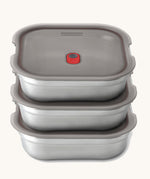 A stack of the Black + Blum square stainless steel leakproof microwave safe lunchboxes 